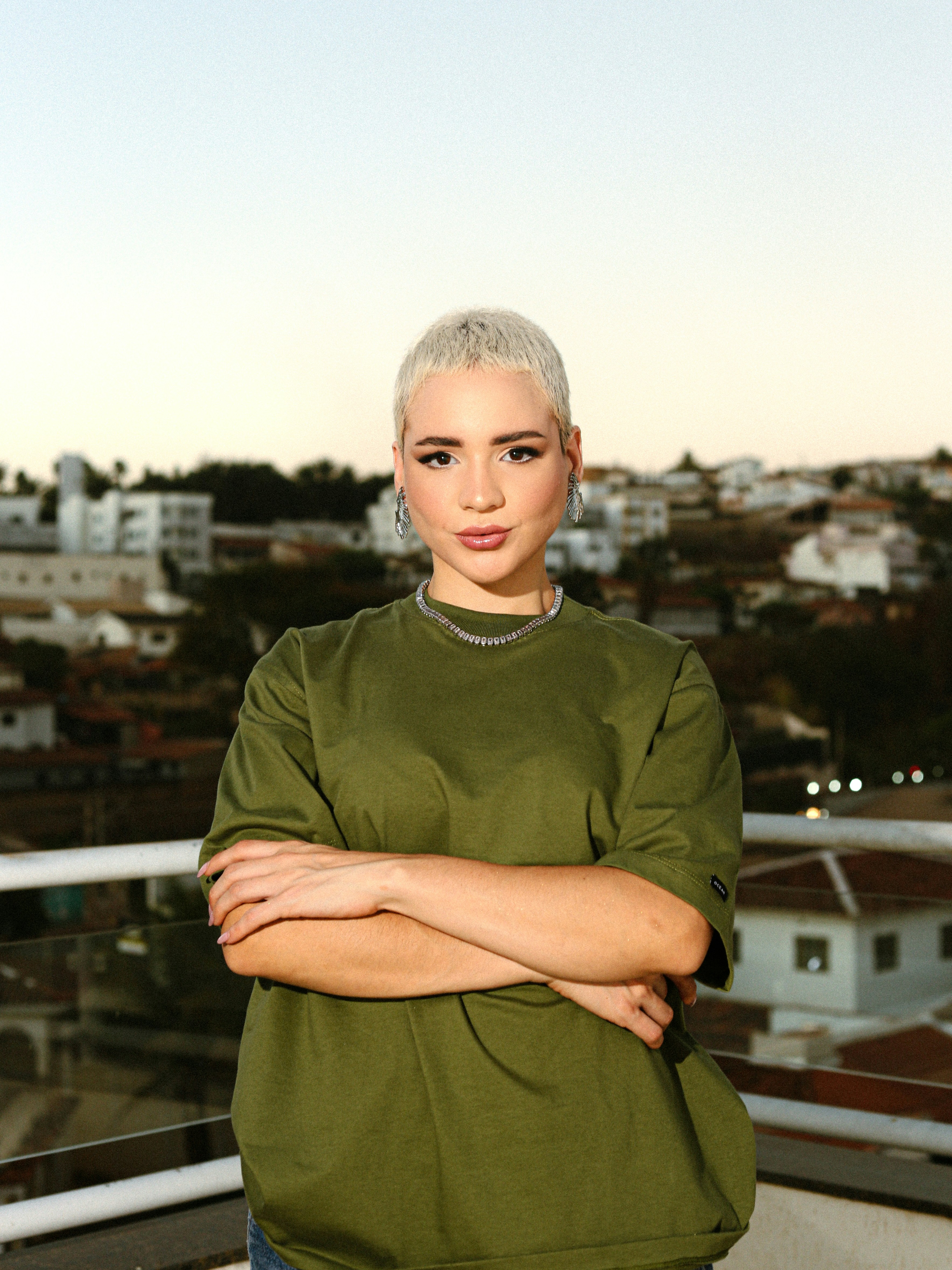 A woman standing on a balcony with her arms crossed