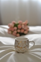 A white coffee cup sitting on top of a bed