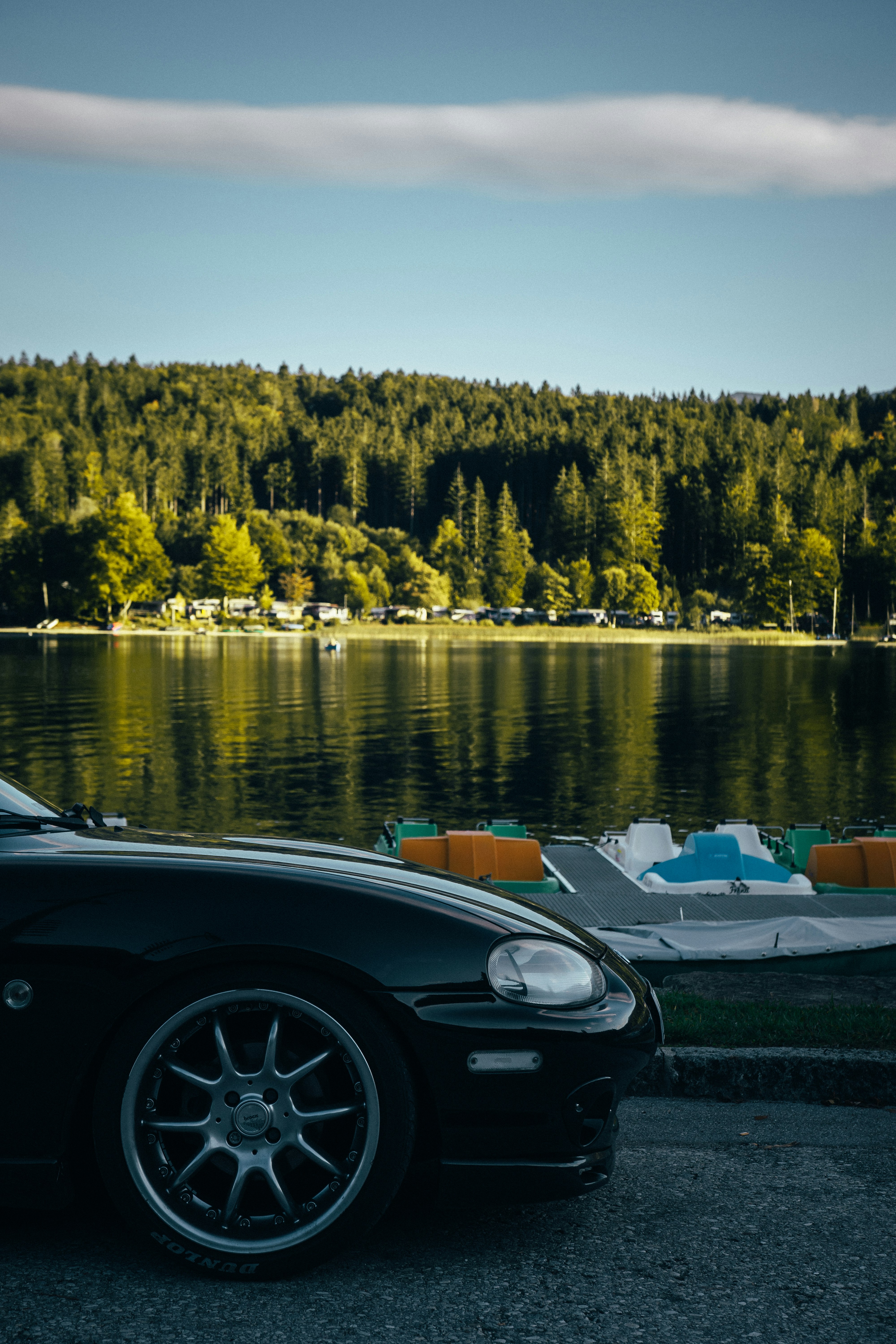 A black sports car parked next to a lake