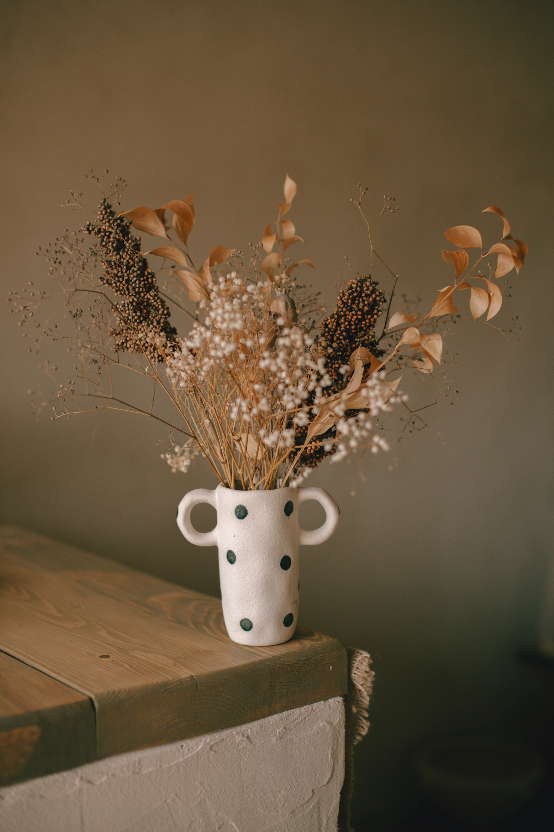 Seasonal flowers displayed in a vase on a wooden table