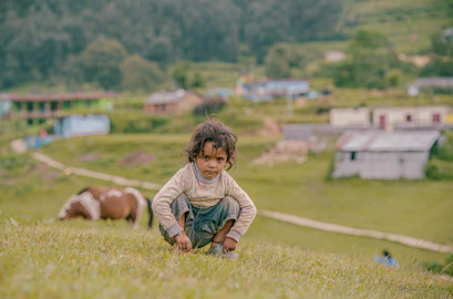 A little boy kneeling down in a field