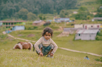A little boy kneeling down in a field