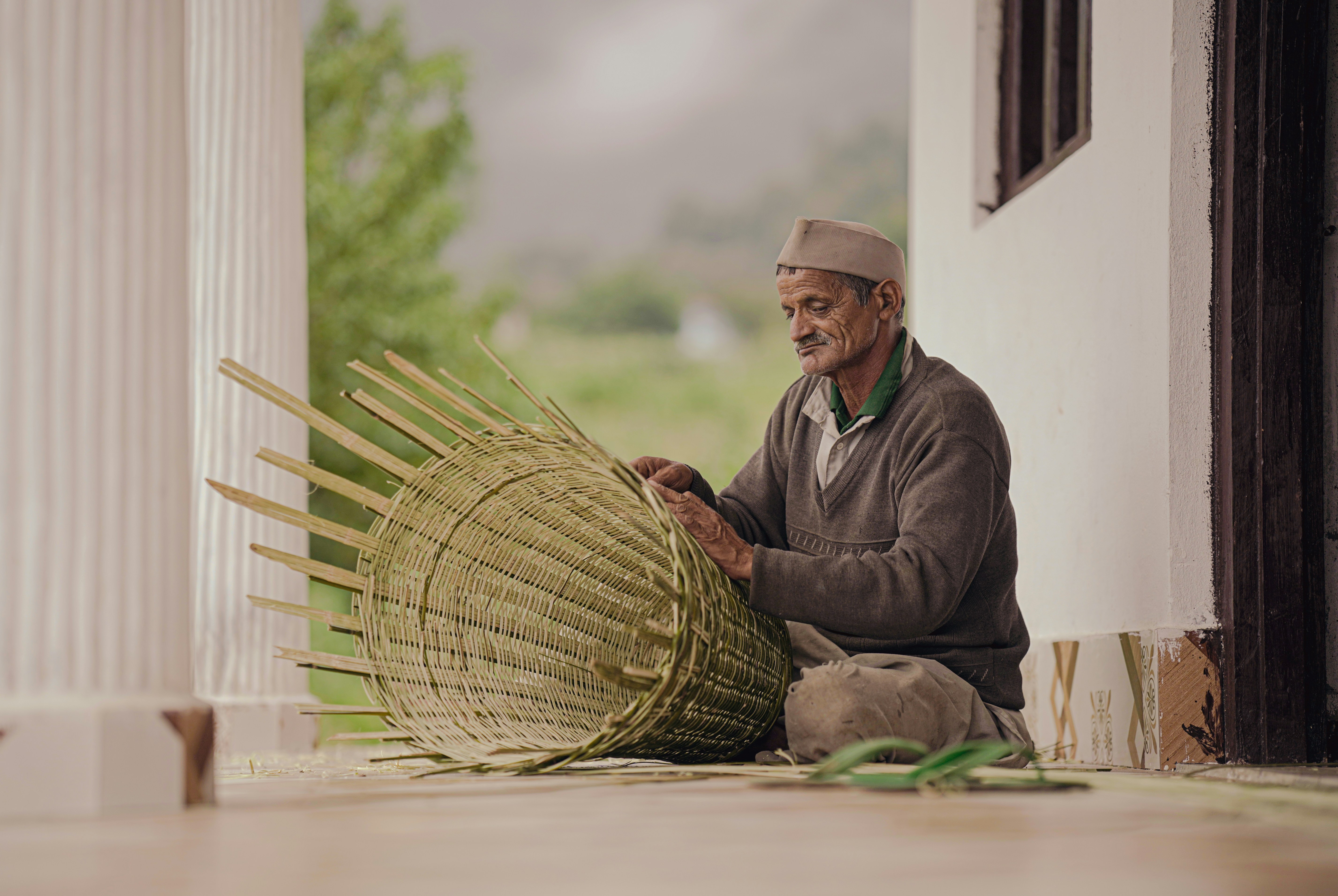 A man sitting on the floor with a large bamboo basket