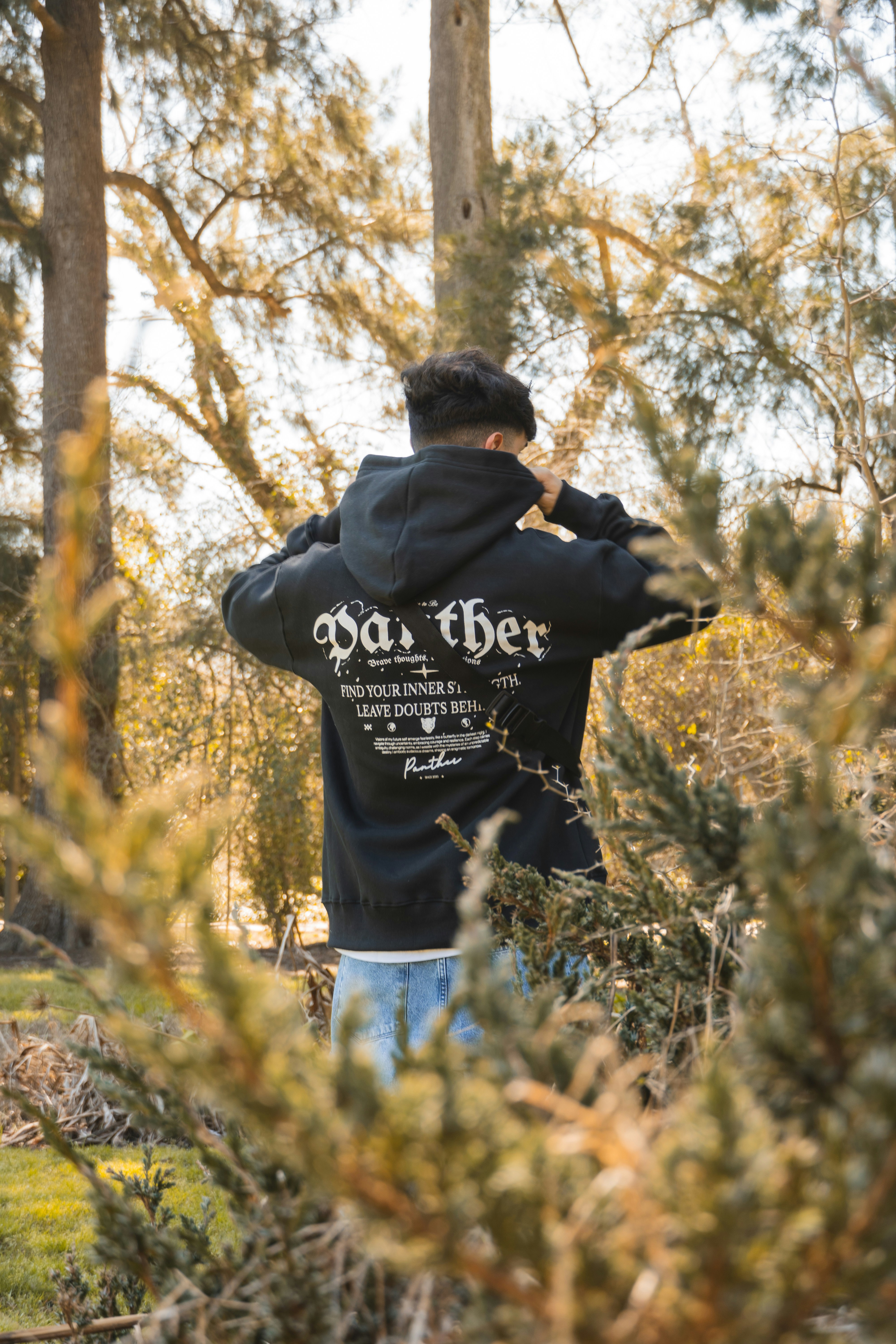 A man in a black jacket standing in a forest