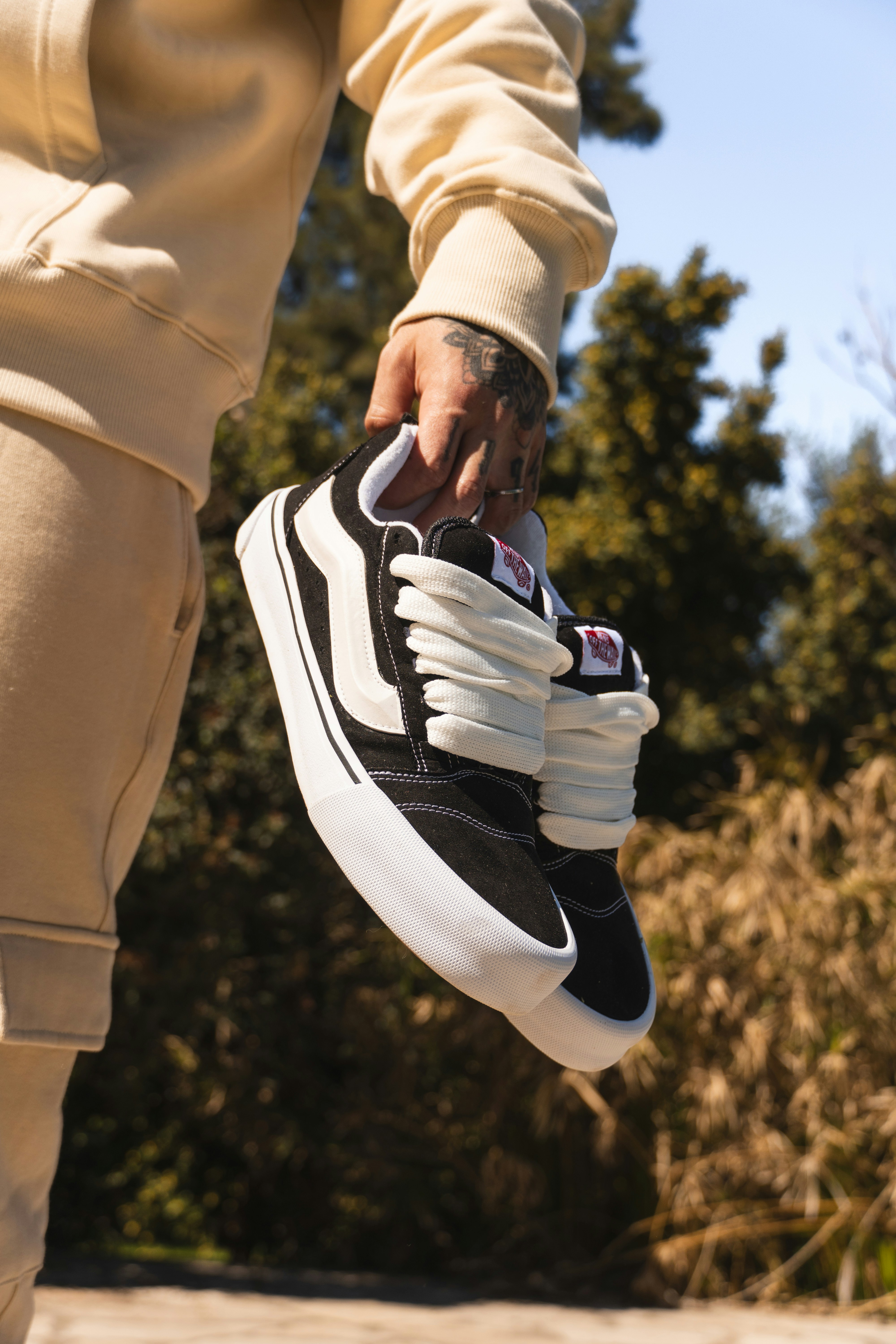 A person wearing black and white sneakers on a skateboard