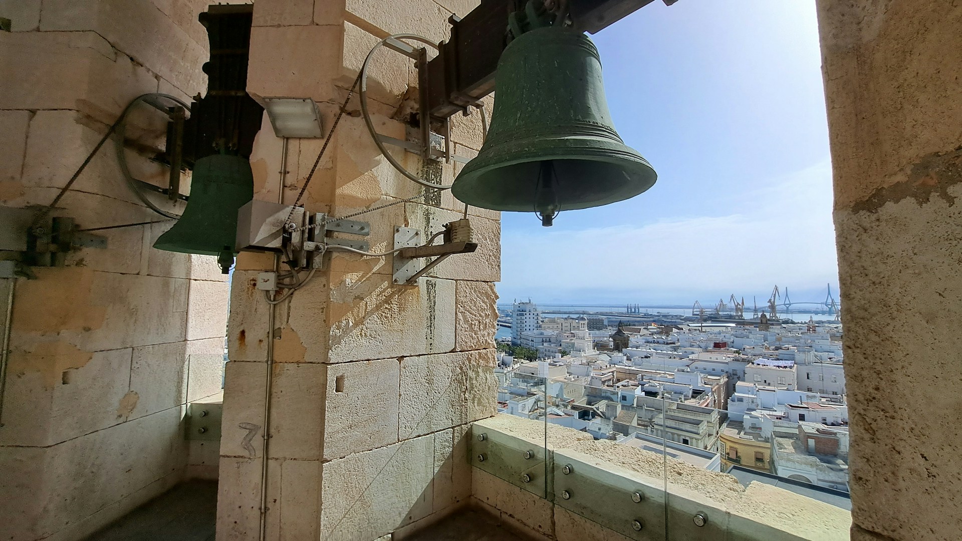 A bell on a wall with a view of a city