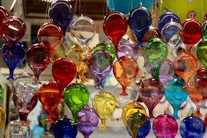 A bunch of colorful wine glasses hanging from a ceiling
