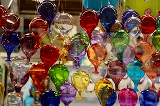 A bunch of colorful wine glasses hanging from a ceiling