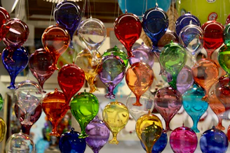 A bunch of colorful wine glasses hanging from a ceiling