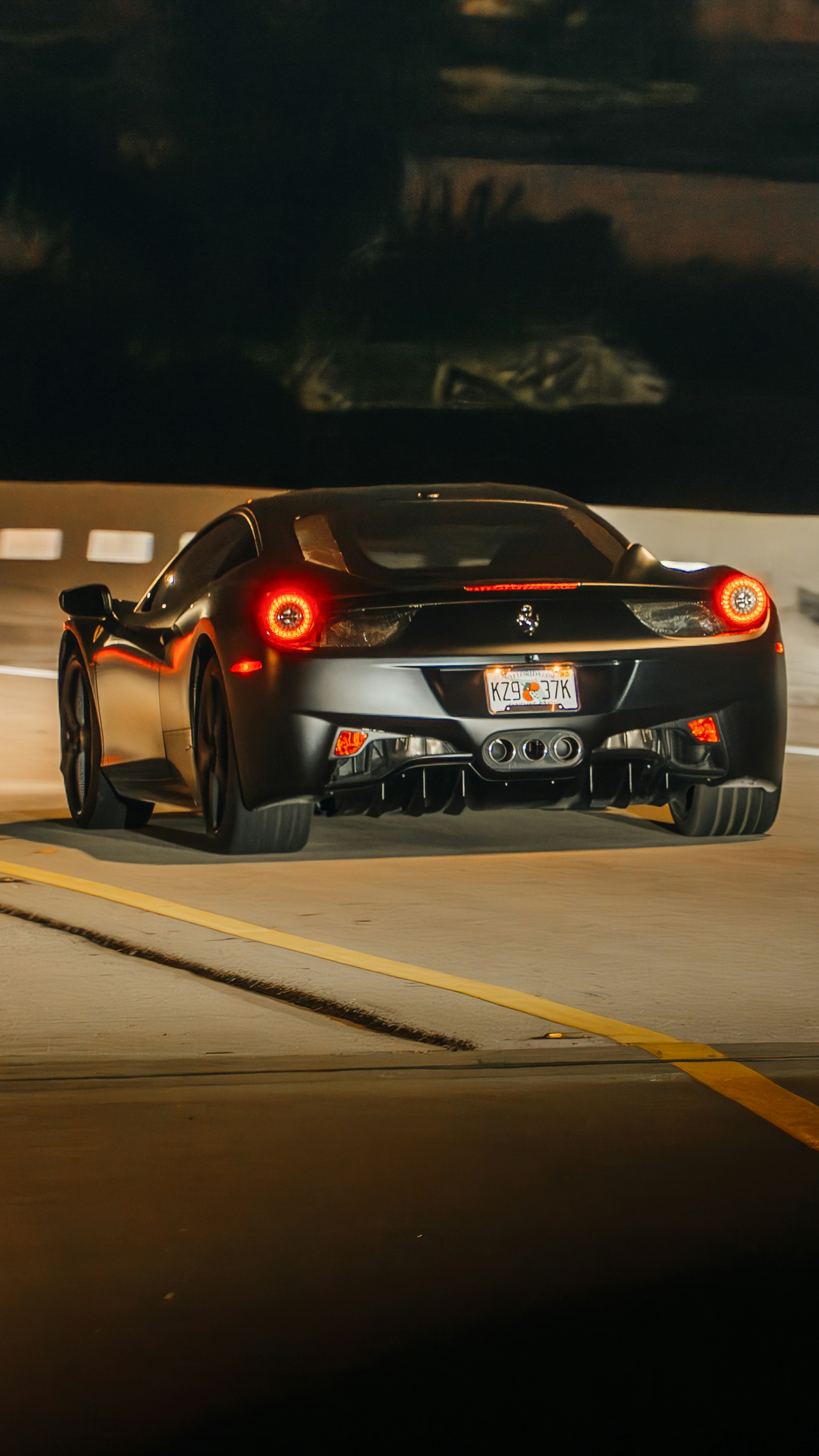 A black sports car driving down a street at night