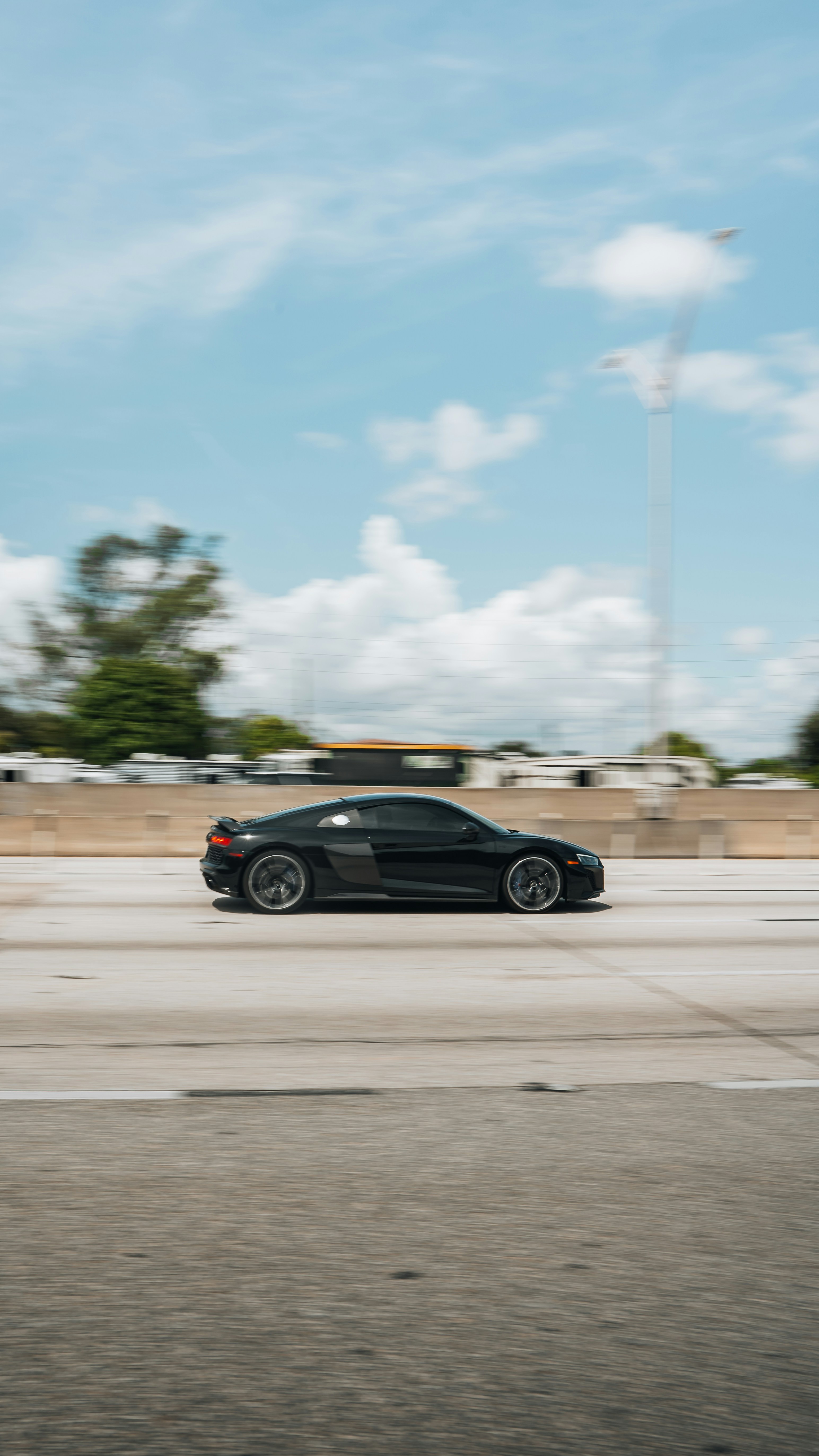A black car driving down a street next to a parking meter