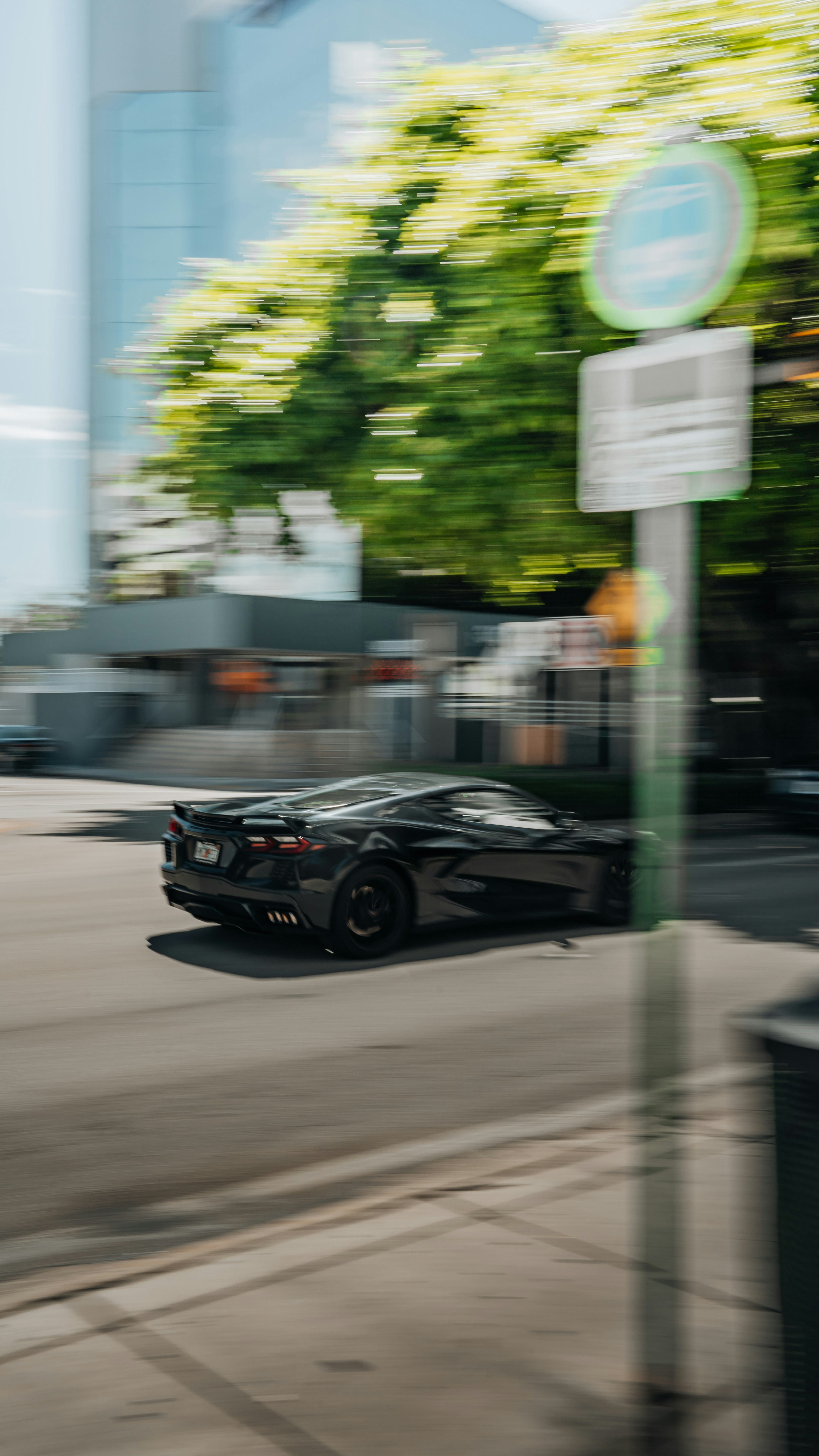 A car driving down a street next to a tall building