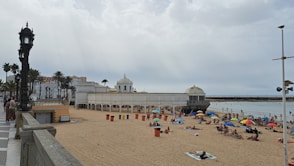 A beach with people sitting and standing on the sand