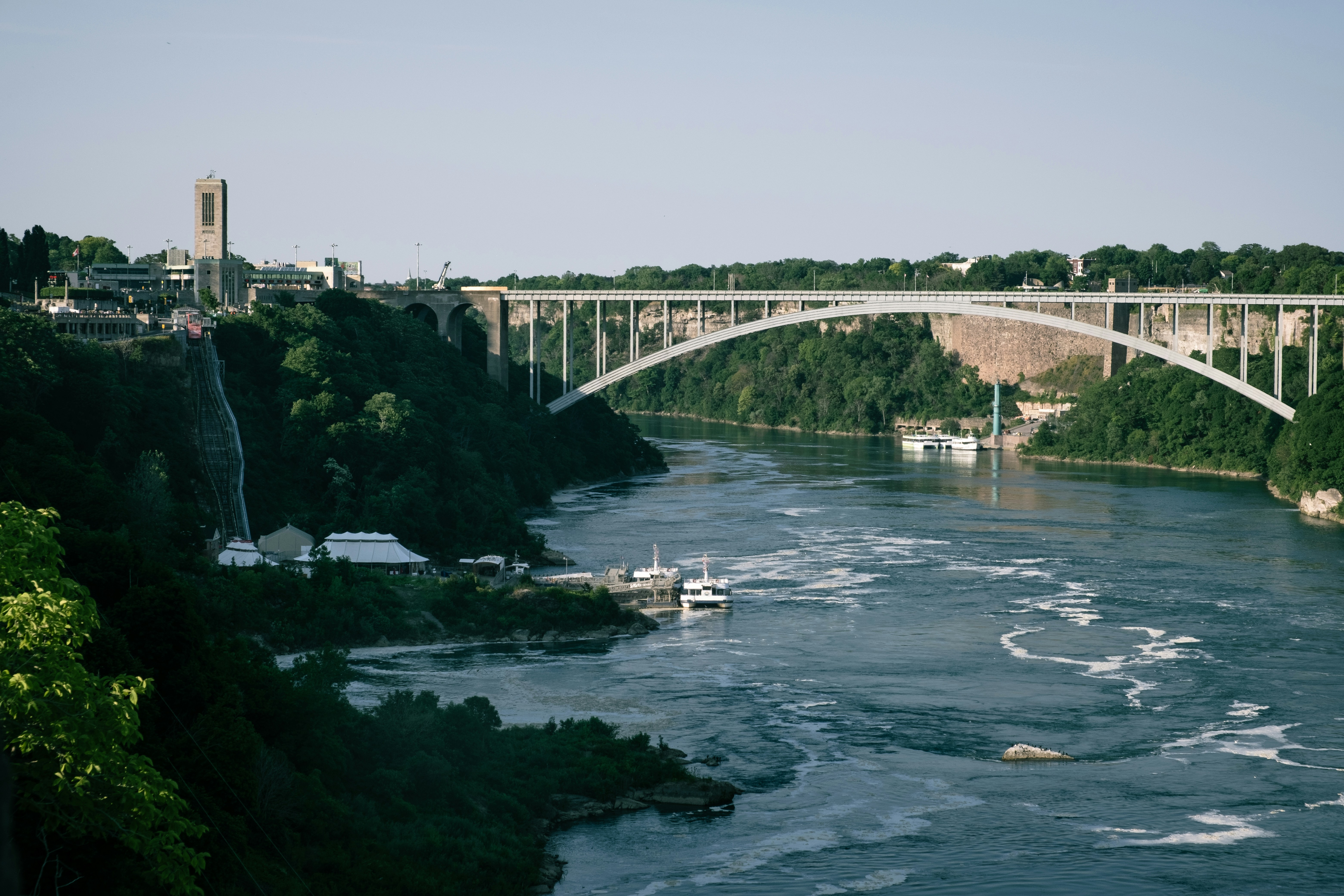 A bridge over a river next to a lush green forest