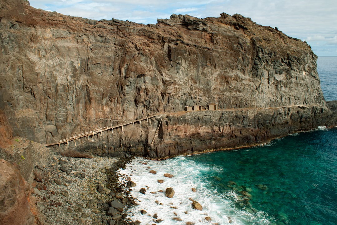 A rocky cliff with a body of water next to it,
