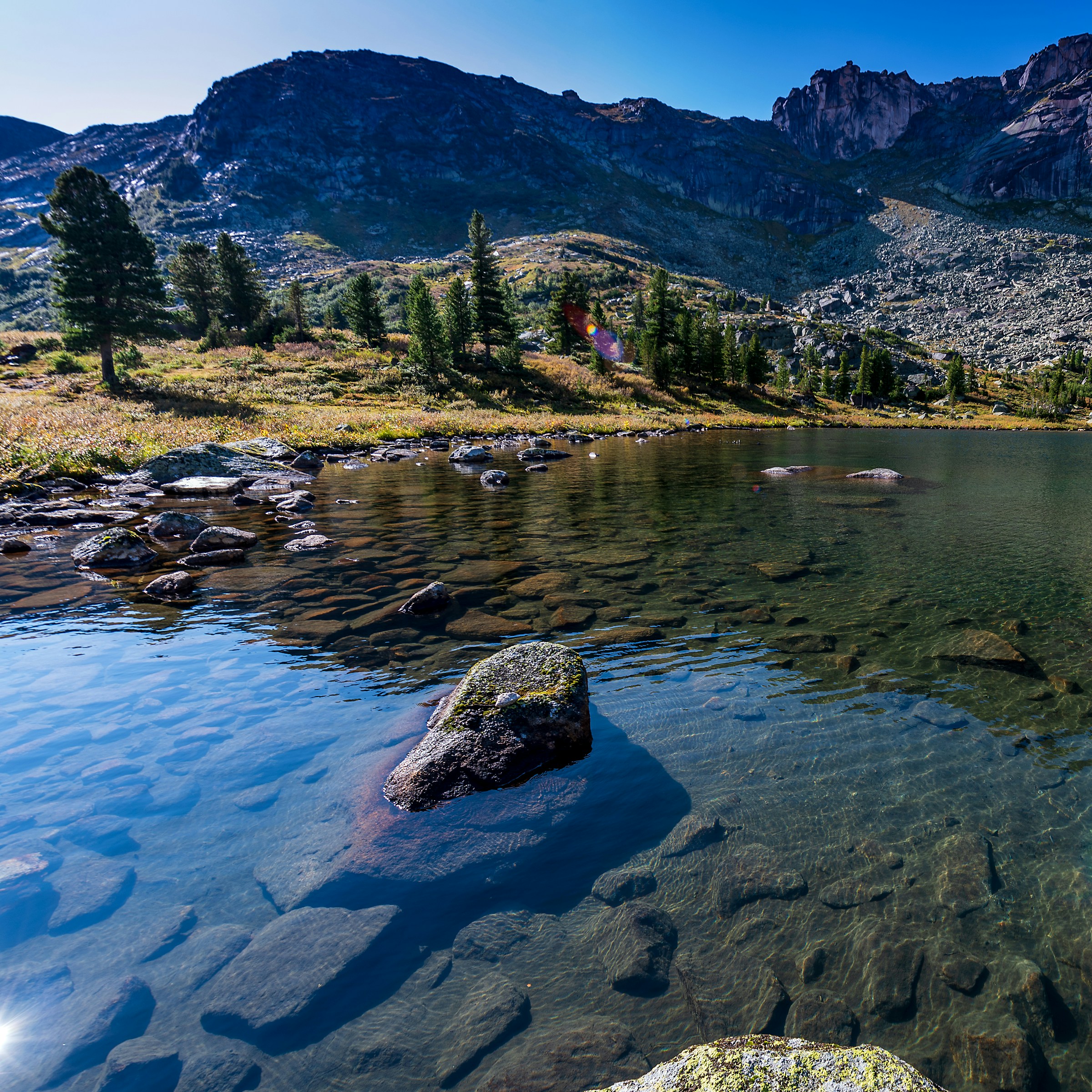A mountain lake surrounded by rocks and trees photo – Free Nature Image ...