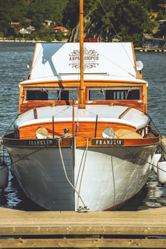 A white and brown boat docked at a dock