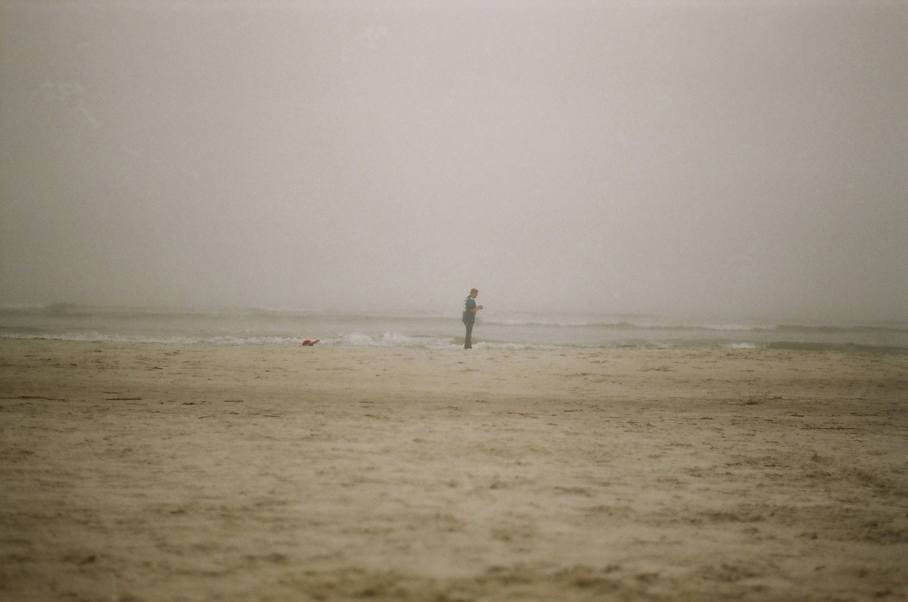 A person standing on a beach with a surfboard