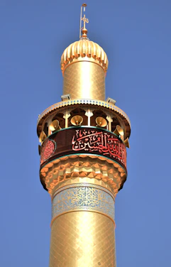 A tall golden tower with a clock on it's side