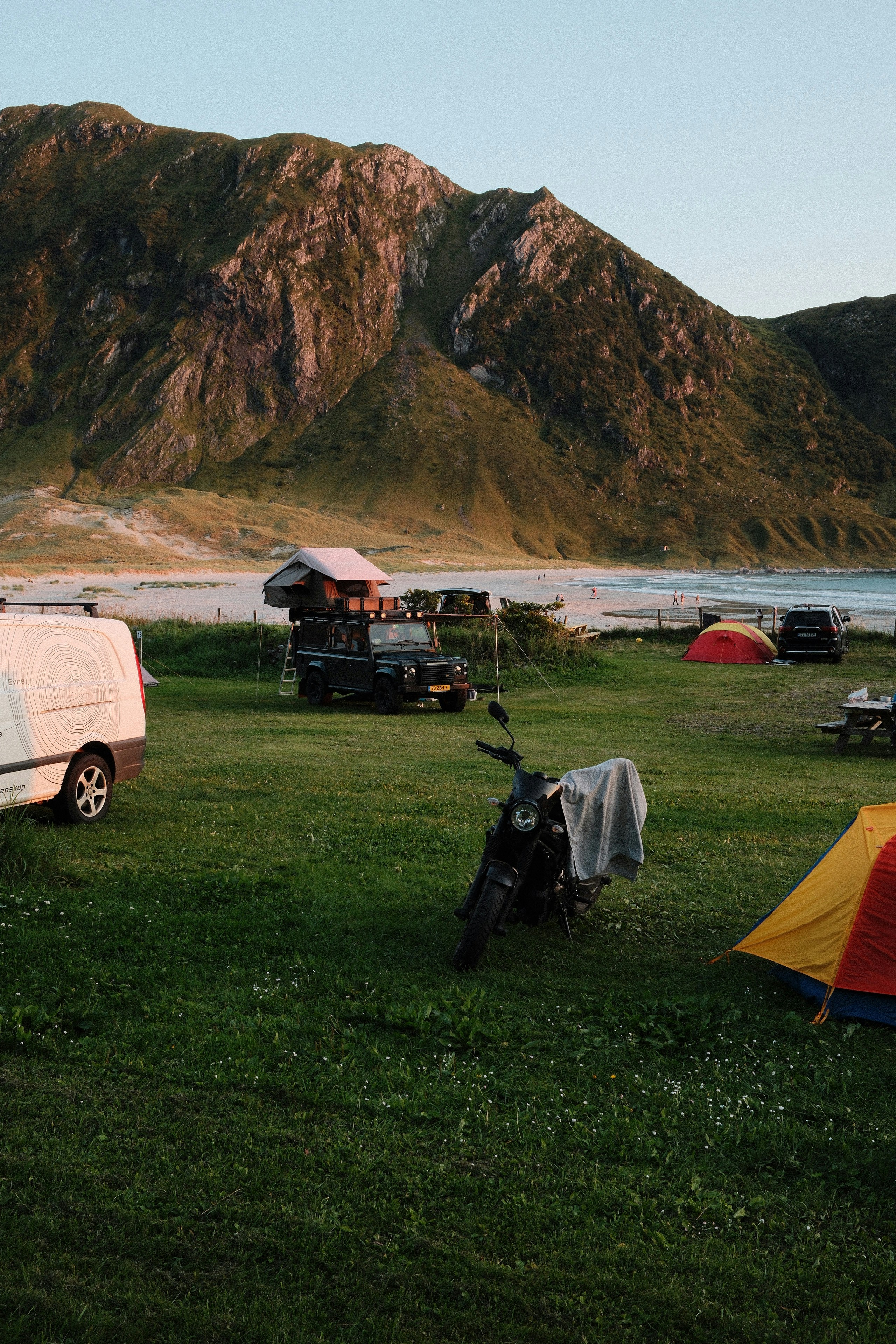 A camper van parked in a field next to a camper trailer