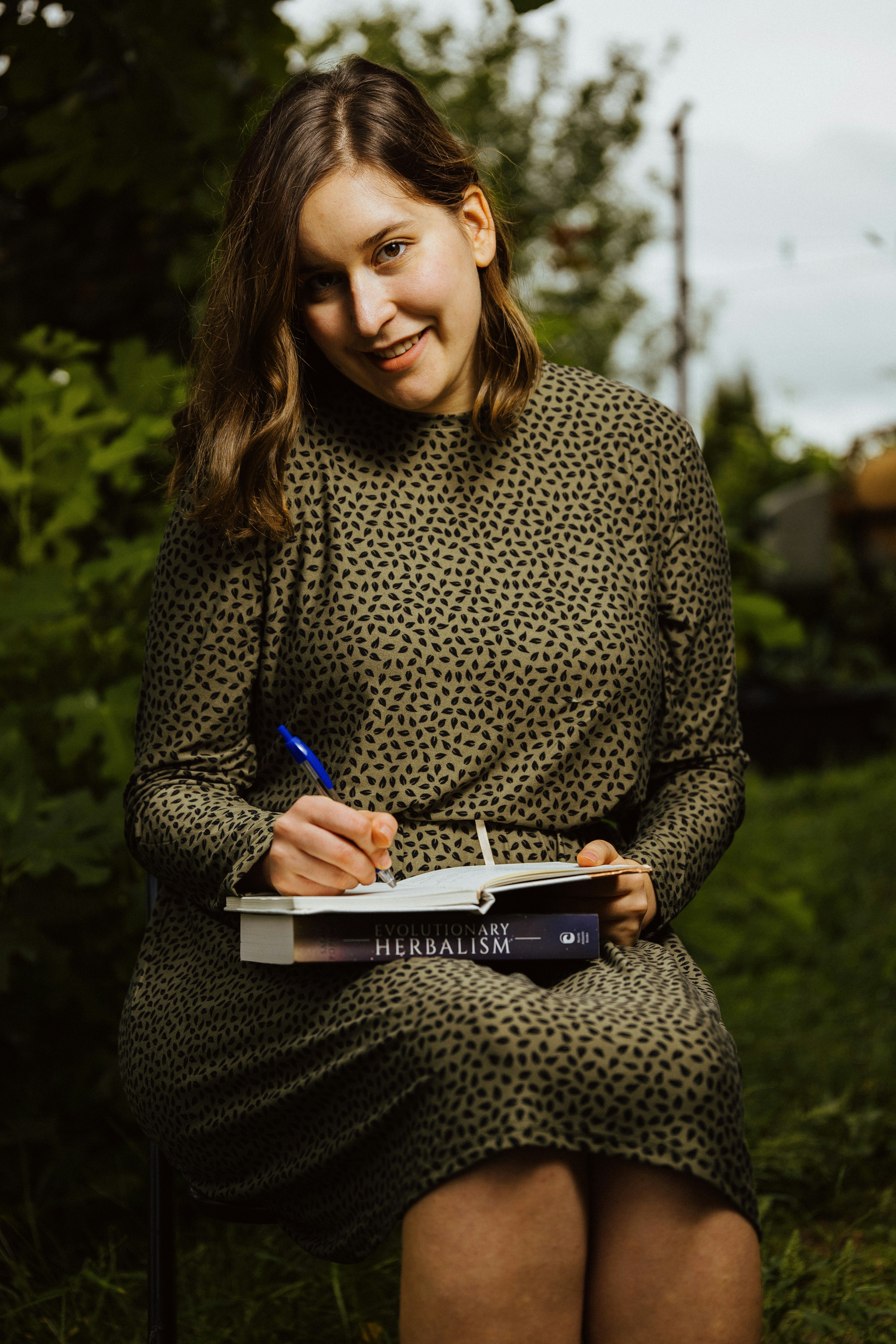 A woman sitting in a chair writing on a book