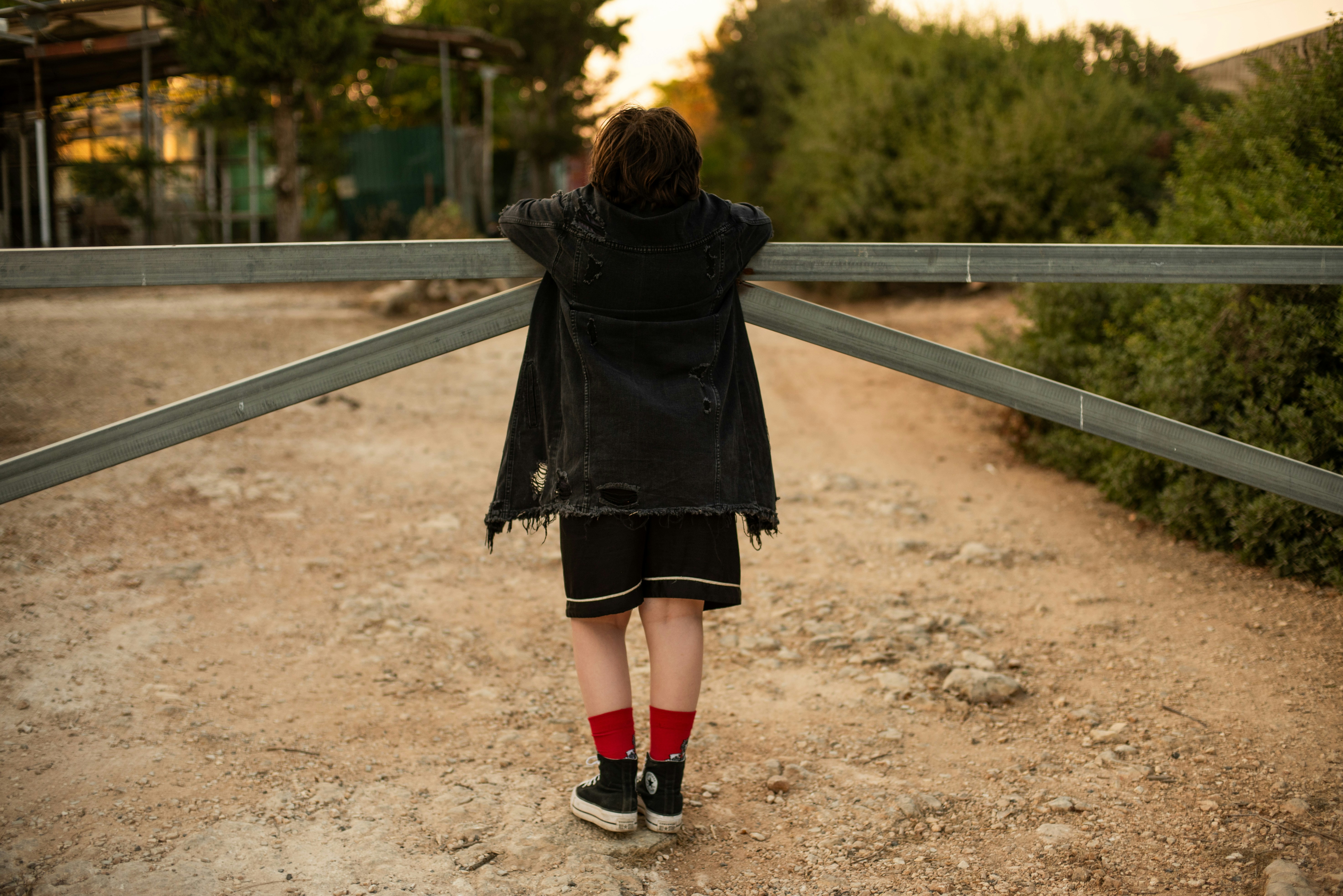 A person standing on a dirt road with their back to the camera