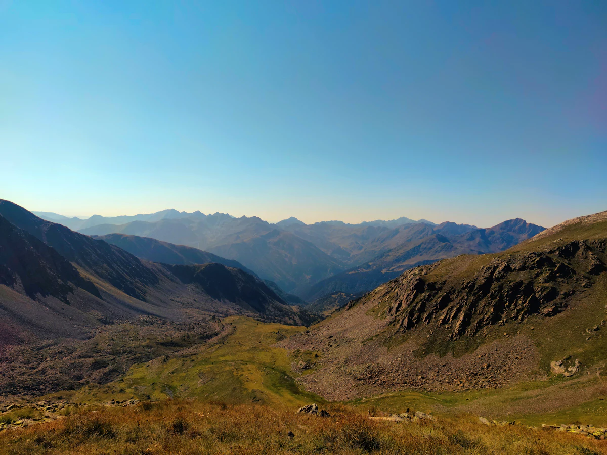 Grassy slopes and rocky ridges in the Sorteny valley above Ordino, with rows of peaks behind
