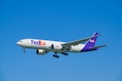 A fedex airplane flying in a clear blue sky