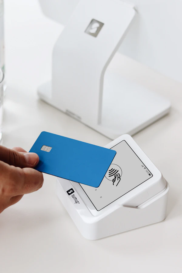 A hand tapping a card against a card payment terminal