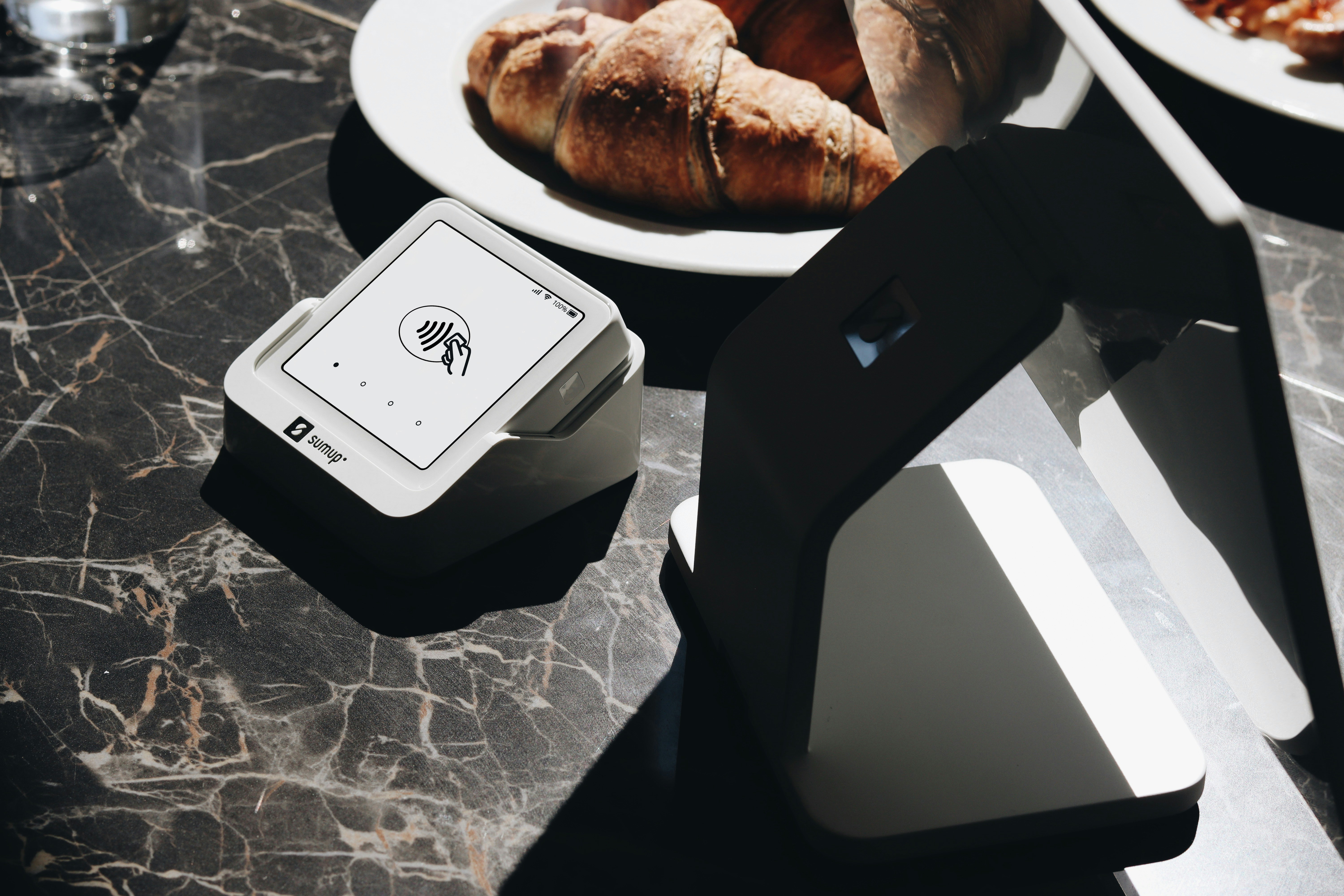A SumUp card reader and POS system are shown on a restaurant table, highlighting the ease of accepting payments during meals. This solution is perfect for restaurants and small businesses that need a reliable and efficient payment system.
