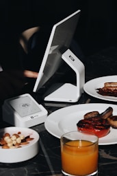 A table topped with plates of food and a laptop computer