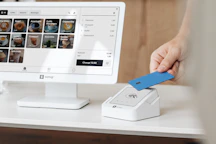 A person holding a blue card in front of a computer