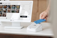 A person holding a blue card in front of a computer