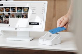 A person holding a blue card in front of a computer