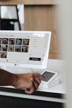 A man holding a cell phone in front of a computer screen