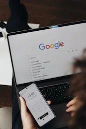 A person holding a cell phone and a laptop