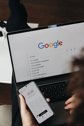 A person holding a cell phone and a laptop