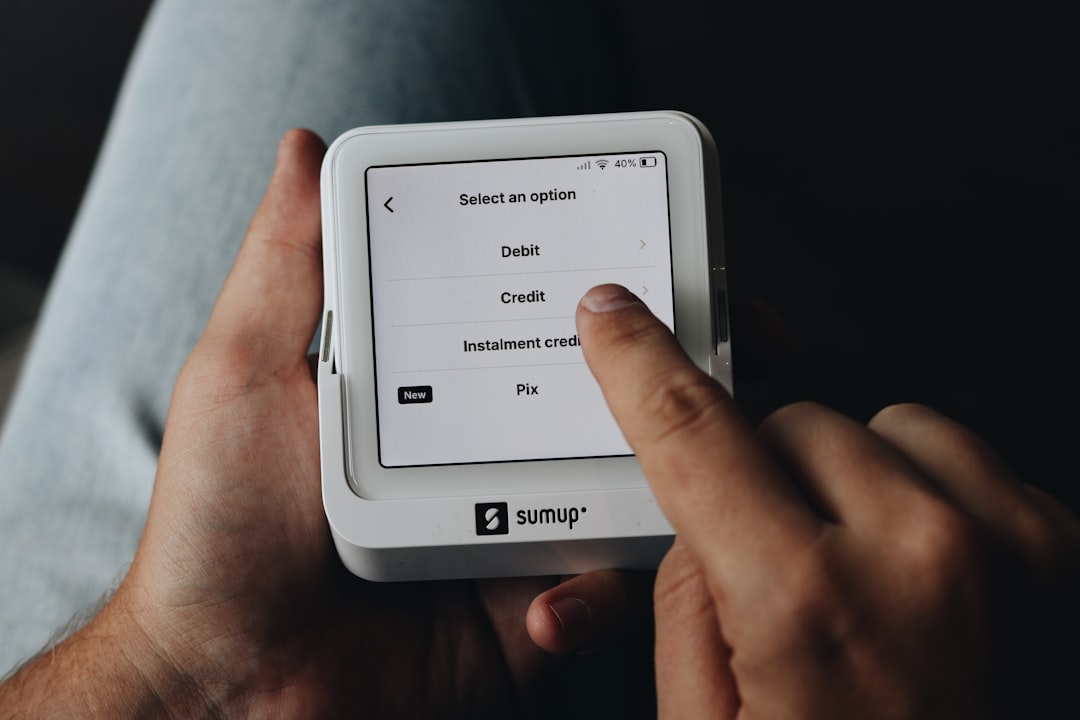 A person is holding a tablet in their hands, A close-up of a person using a SumUp card reader, selecting a payment option on the touchscreen. The options displayed include debit, credit, instalment credit, and Pix, highlighting the versatility of the payment methods available through SumUp. The device is held comfortably in the user’s hand, showcasing its portability and user-friendly interface. This image emphasizes the ease and variety of payment solutions for small businesses and merchants.