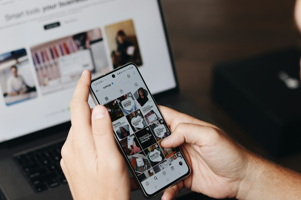 Person scrolling a blog on a phone next to a laptop