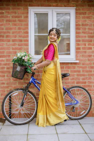 A woman in a yellow sari standing next to a bike