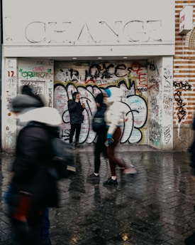 A group of people walking past a graffiti covered building