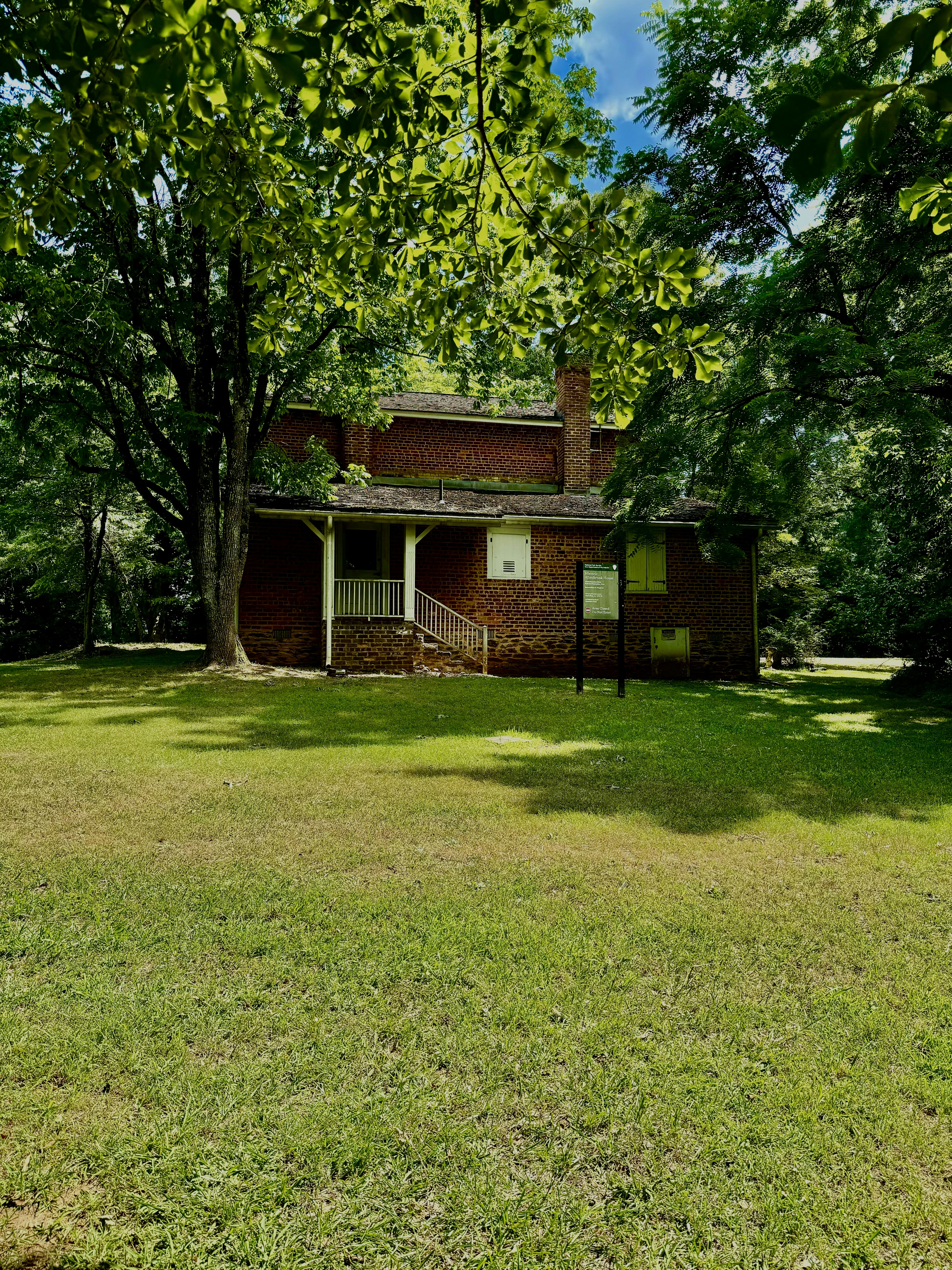 A brown house sitting in the middle of a lush green field