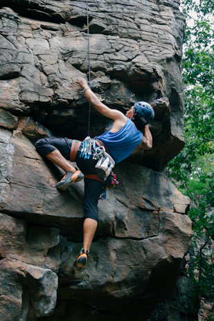 A man climbing up the side of a large rock