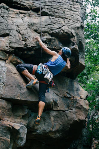 A man climbing up the side of a large rock