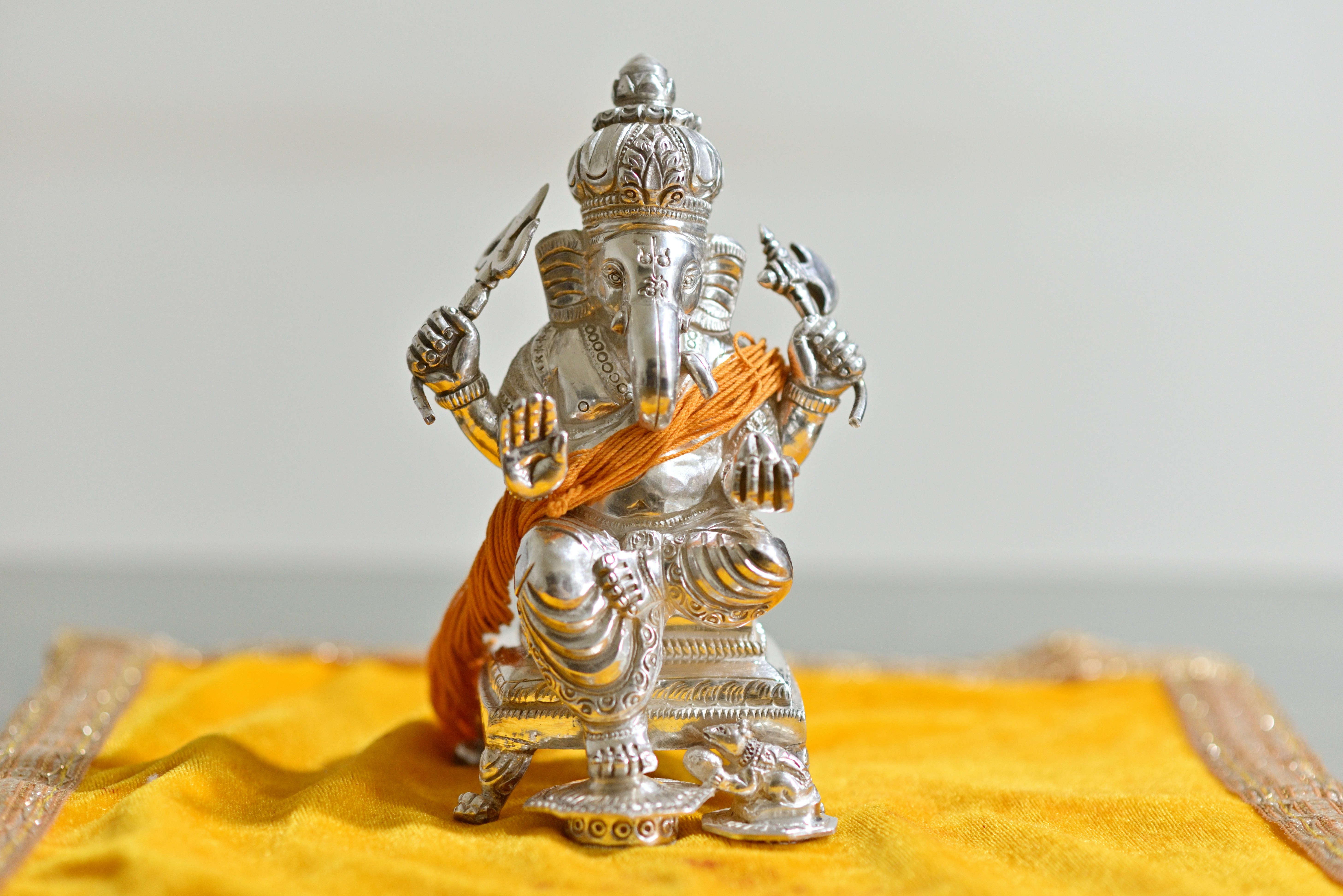 A silver statue of a god on a yellow cloth
