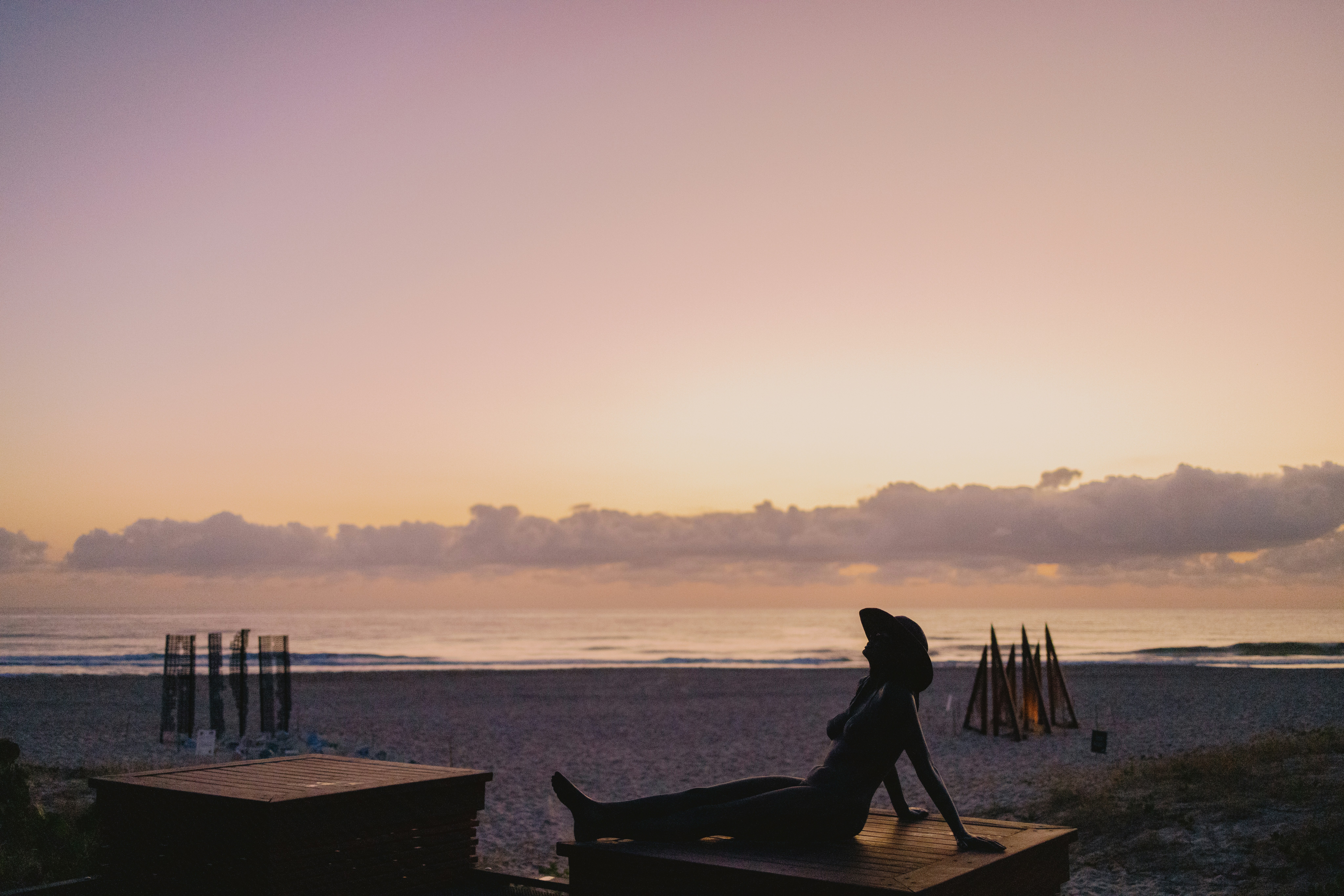 A woman sitting on a bench on the beach
