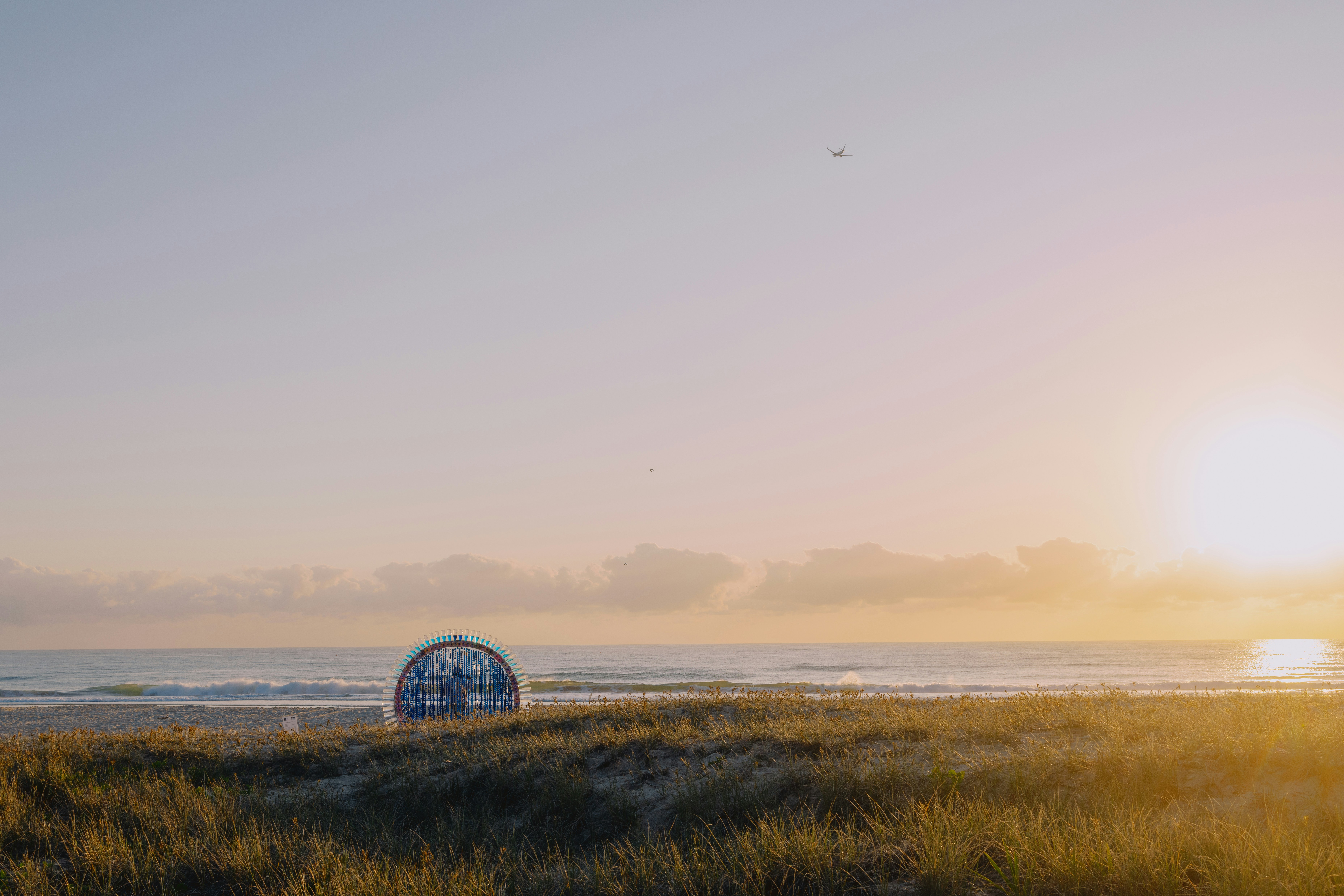 The sun is setting over the beach with a ball in the foreground