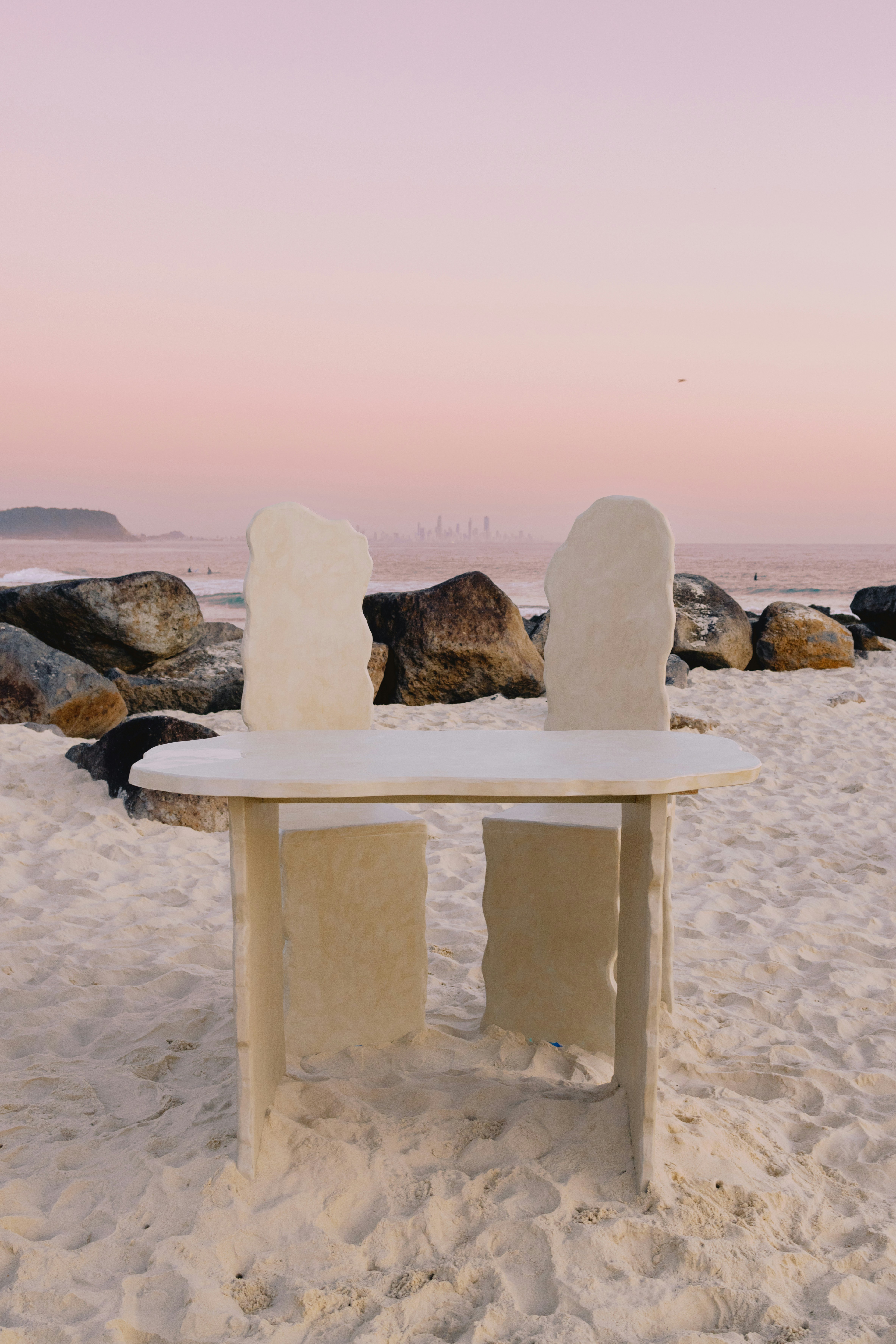 A white table and chair on a sandy beach