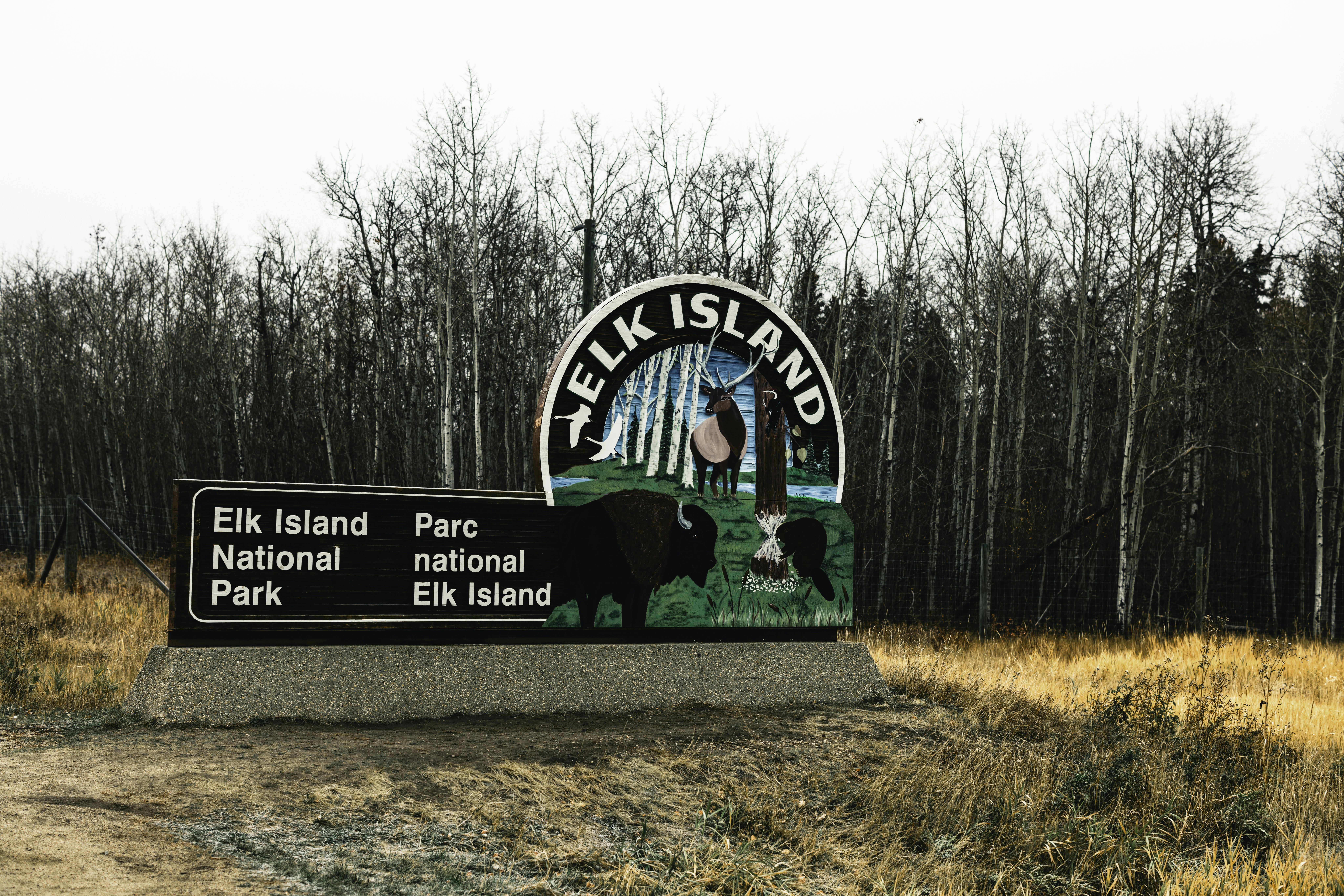A sign in front of a field with trees in the background