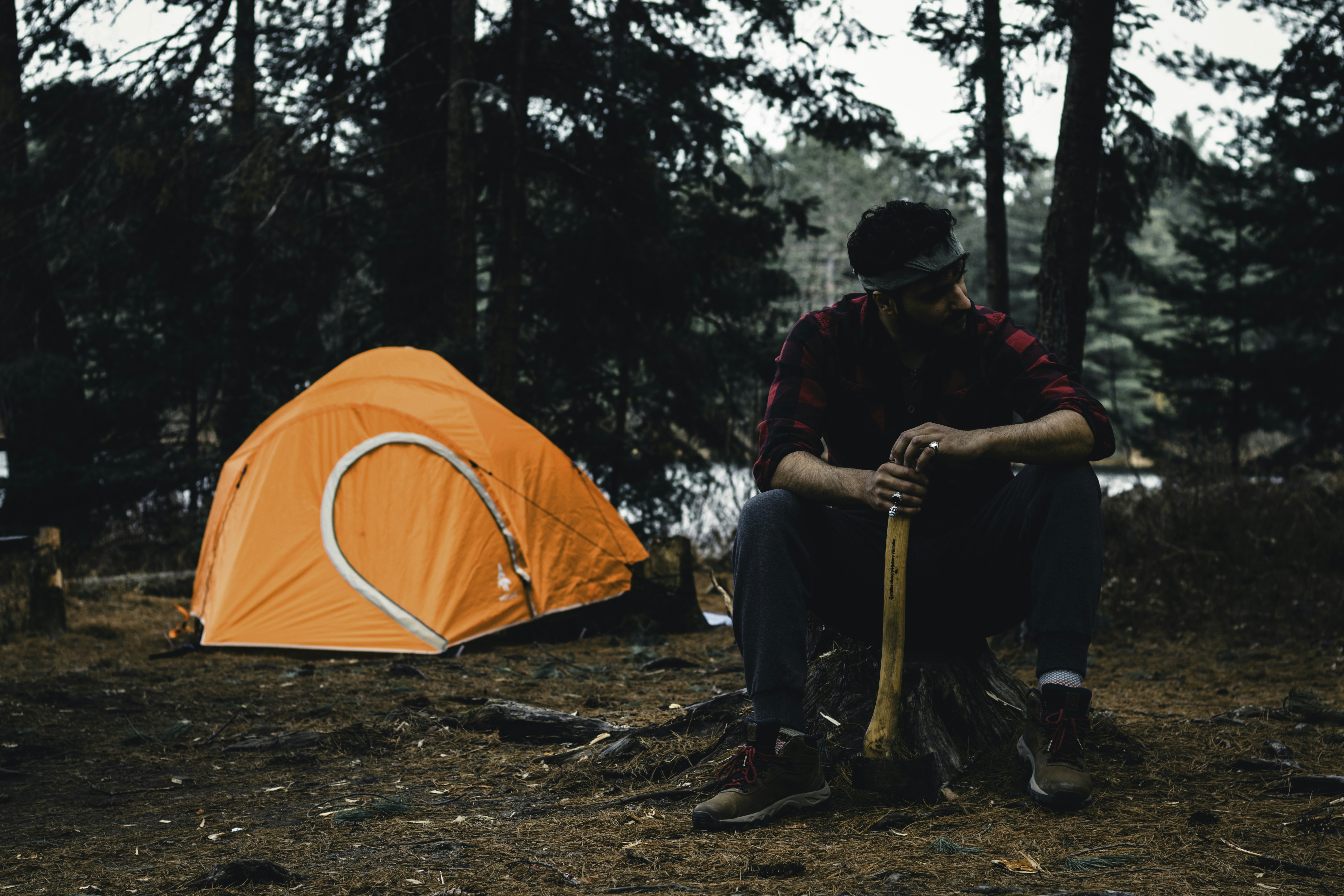 A man sitting next to a tent in the woods